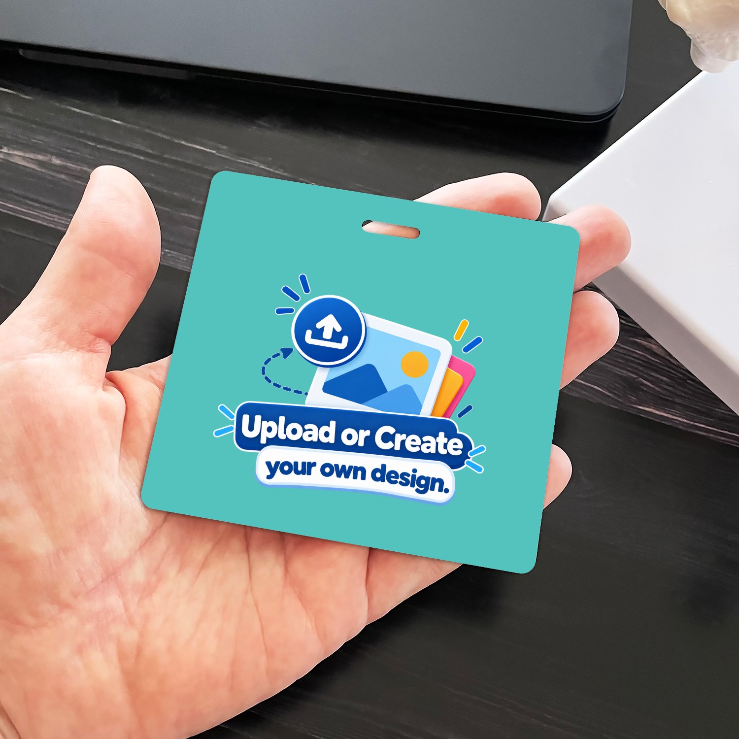 Teal horizontal ID badge with Upload or Create your own design graphic held in an open palm