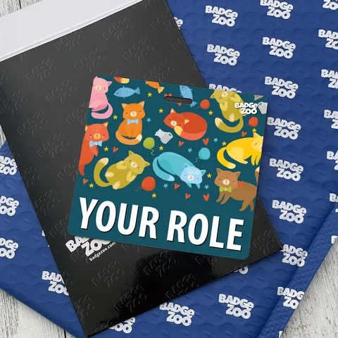 Square teal kitten badge buddy with YOUR ROLE text on a black envelope against a blue Badge Zoo mailer