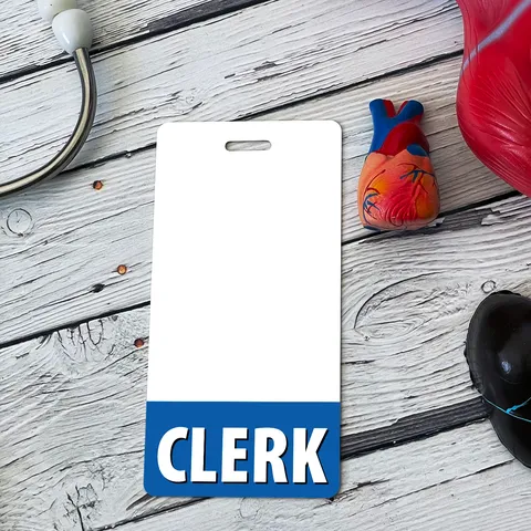 Vertical CLERK badge buddy on white wood planks beside a plastic anatomical heart model and a stethoscope