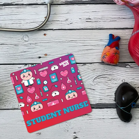 Square pink-to-red badge buddy with cute nurse and medical icons, bold teal STUDENT NURSE text, on a white wooden table