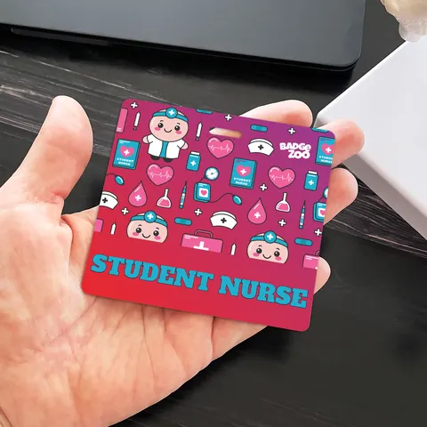Hand holding a student nurse badge buddy above a dark desk