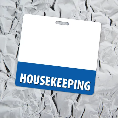 Horizontal housekeeping badge buddy with blue bottom strip lying on crinkled silver aluminum foil