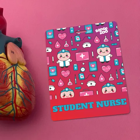 Vertical multicolor student nurse badge buddy with cartoon nurses and hearts, lying on grey surface beside a stethoscope