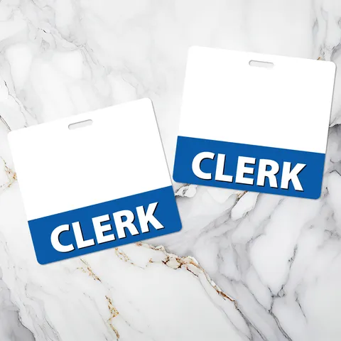 Two horizontal CLERK badge buddies with white tops and blue bands lying side by side on white marble