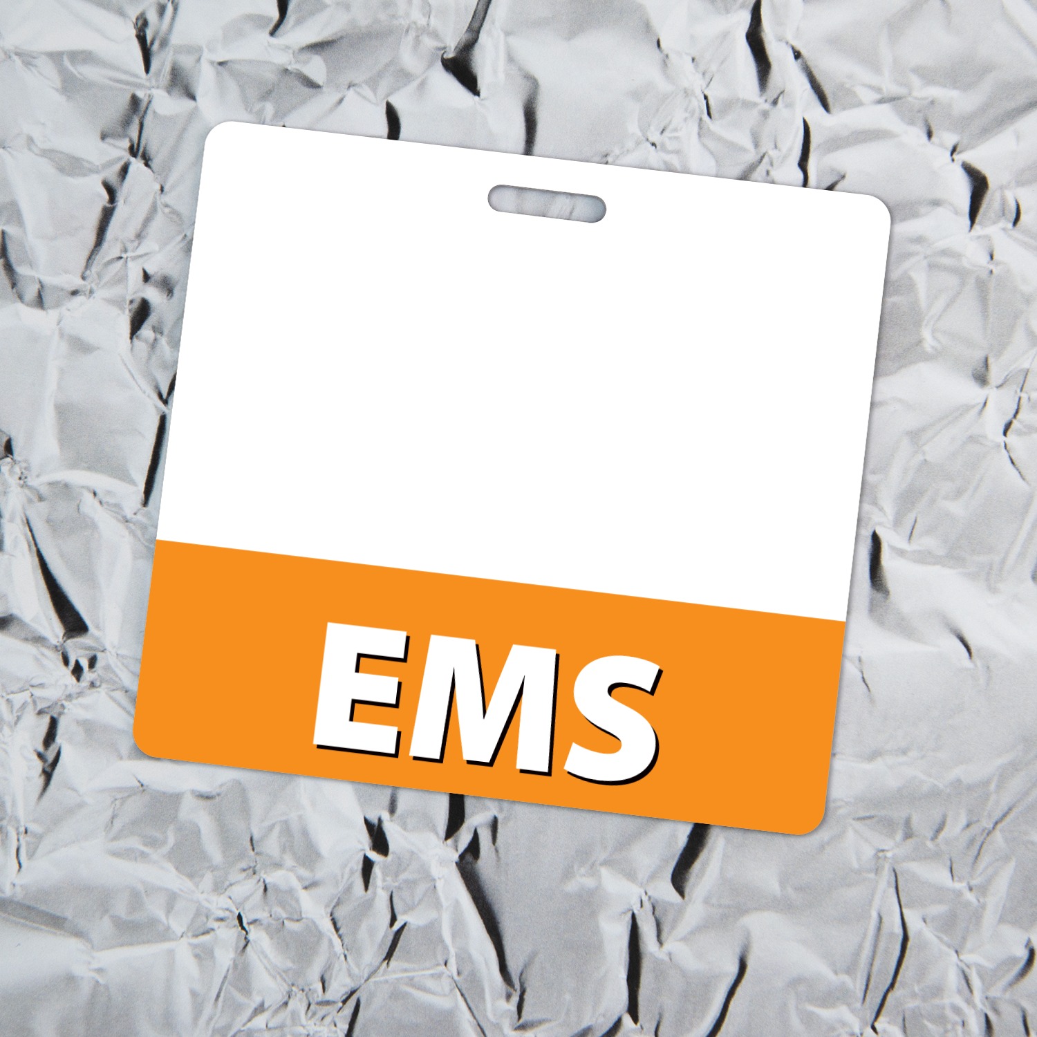 Horizontal white EMS badge buddy with orange bottom band lying tilted on crinkled silver aluminum foil