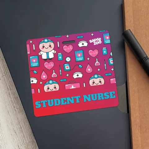Student nurse badge buddy resting on a dark folder beside a pen