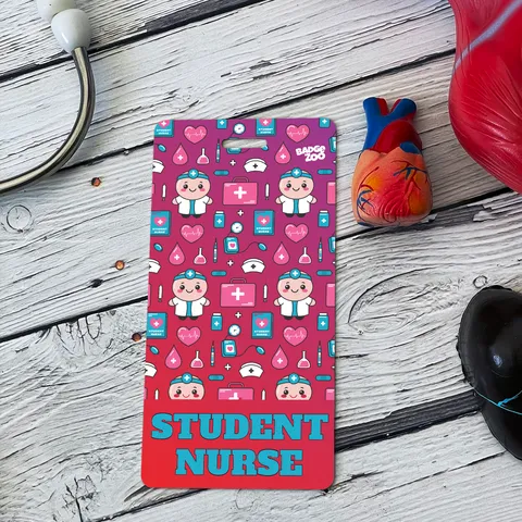 Student Nurse badge buddy with pink medical icon pattern beside a red anatomical heart model on white wood