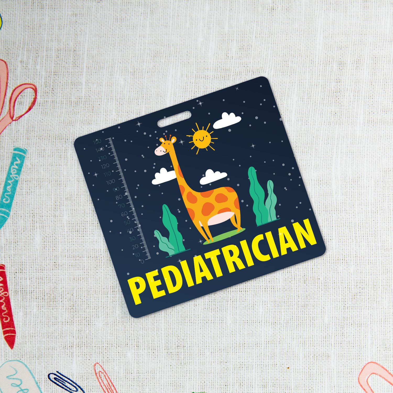 Navy pediatrician badge buddy with giraffe and yellow lettering on linen with colourful kids craft scissors and crayons