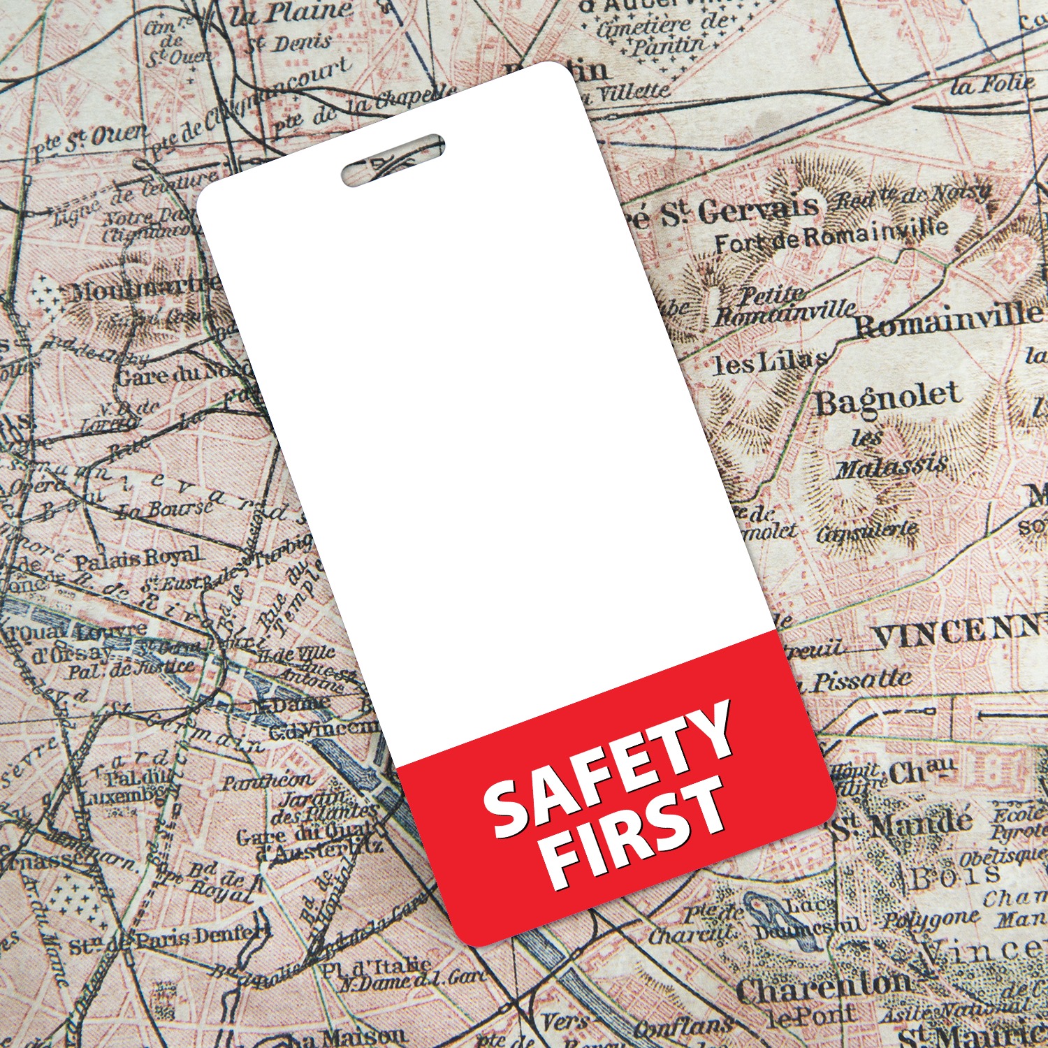 Vertical SAFETY FIRST badge buddy with red bottom band lying over a vintage pink Paris map