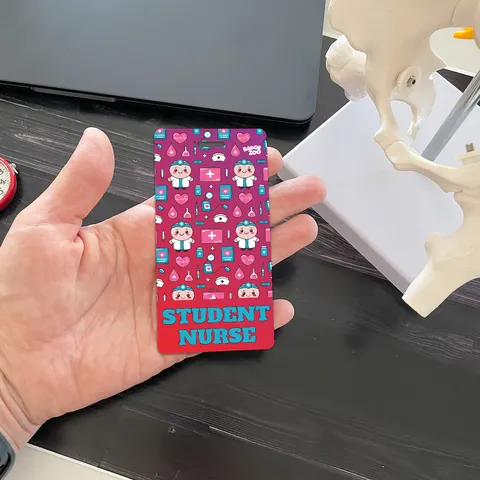 Hand holding a vertical student nurse badge buddy next to an anatomy model
