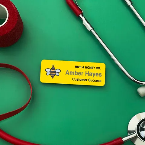 Yellow bee name tag reading Amber Hayes beside a red stethoscope on a green background