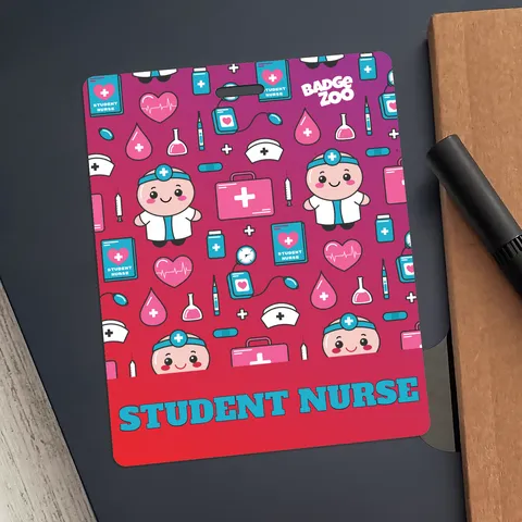 Student nurse ID badge with pink medical pattern and teal text, placed on a dark folder beside a black pen