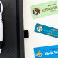 Three custom name tags for pets and professionals next to a black notebook and multi-color pen