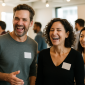 Group of smiling professionals wearing blank name tags while networking at a lively indoor event.